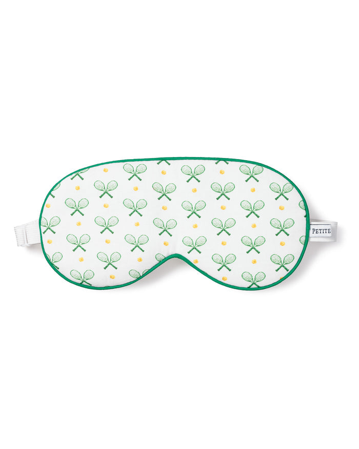 The Petite Plume Adults Sleep Mask in Match Point showcases a tennis print with green rackets and yellow balls, complete with green trim and an adjustable white strap. Pair it with matching pajamas for a chic set. The brand label adds a touch of elegance to the side.