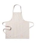 The Adult's Twill Apron in Camel Gingham features a beige and white checkered pattern, a neck loop, front pockets, and waist ties, shown laid flat on a white background.