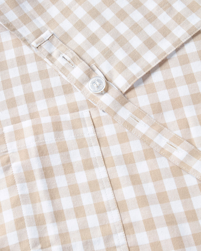 The Adult's Twill Apron in Camel Gingham features a beige and white checkered pattern, a neck loop, front pockets, and waist ties, shown laid flat on a white background.