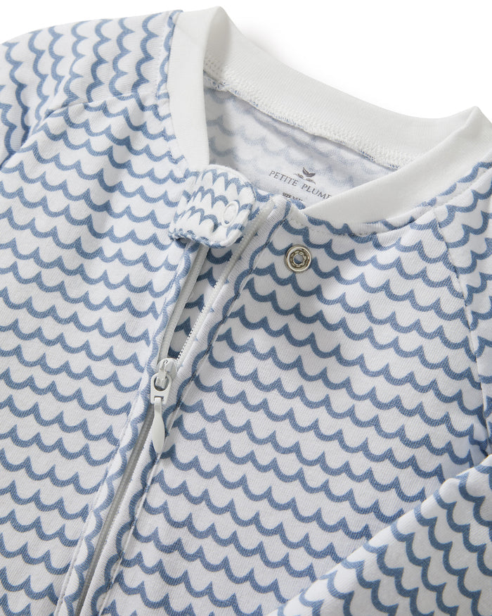 The Baby's Pima Peekaboo Romper in La Mer features a blue wave pattern, white cuffs on the sleeves and legs, and a diagonal zipper from the neckline to the left ankle.