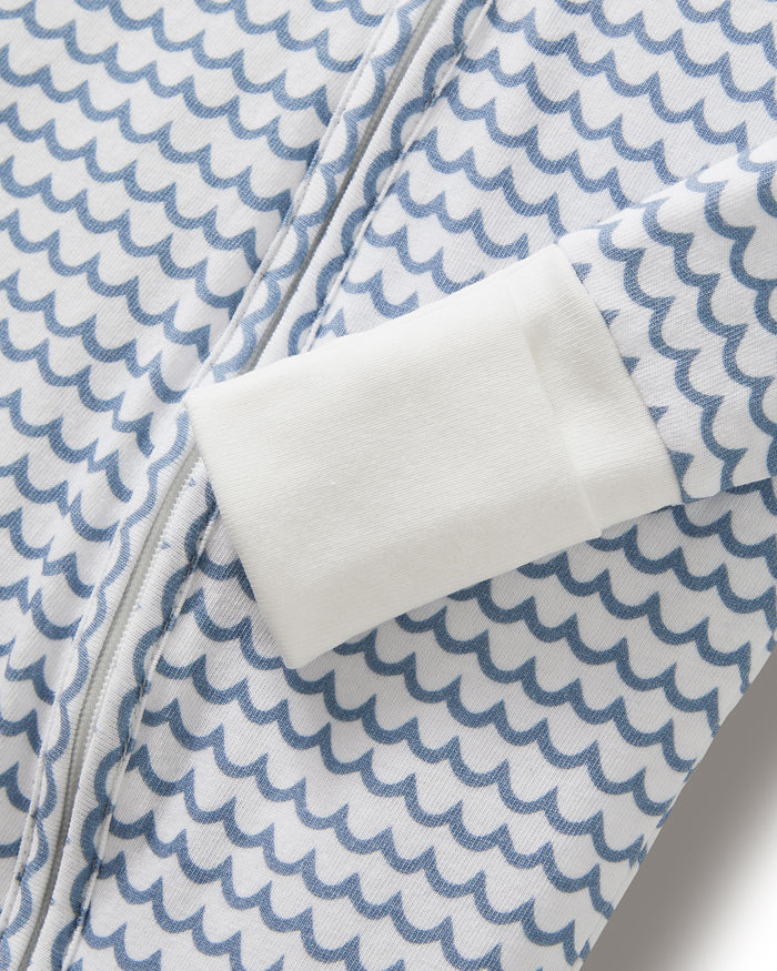 The Baby's Pima Peekaboo Romper in La Mer features a blue wave pattern, white cuffs on the sleeves and legs, and a diagonal zipper from the neckline to the left ankle.