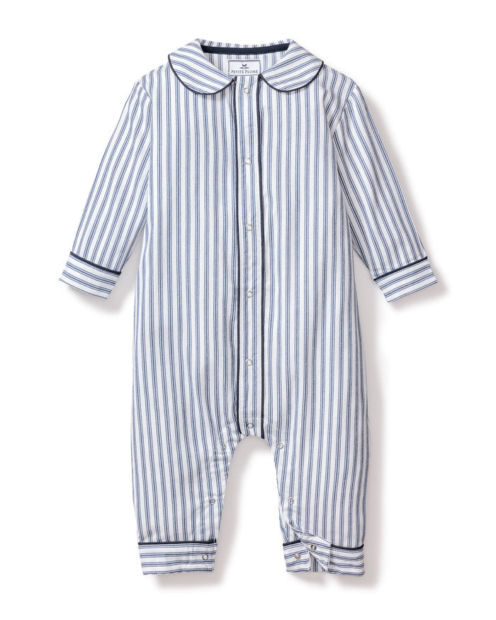 The Babys Twill Cambridge Romper by Petite Plume is crafted from soft brushed twill, perfect for sleepwear. It features long sleeves, a collar, and vertical navy stripes. Front buttons add style, while solid blue bands at the cuffs ensure cozy elegance for your little one.