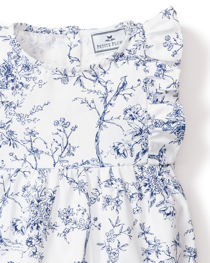 Close-up of the Babys Twill Ruffled Romper in Timeless Toile by Petite Plume, featuring intricate blue floral patterns on white fabric with a ruffled shoulder detail reminiscent of the Victorian era.