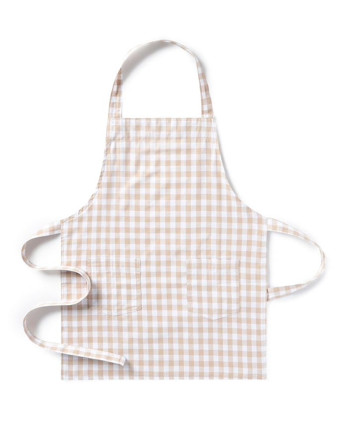 The Kid's Twill Apron in Camel Gingham, featuring a beige and white gingham pattern, two front pockets, and long waist ties, is displayed on a white background.