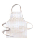 The Kid's Twill Apron in Camel Gingham, featuring a beige and white gingham pattern, two front pockets, and long waist ties, is displayed on a white background.