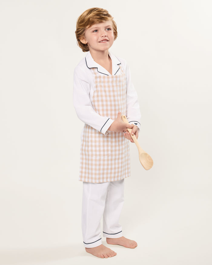 The Kid's Twill Apron in Camel Gingham, featuring a beige and white gingham pattern, two front pockets, and long waist ties, is displayed on a white background.