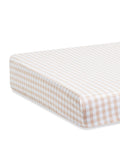 A close-up view of a mattress fitted with the Luxe Premium Percale Crib Sheet in Camel Gingham.