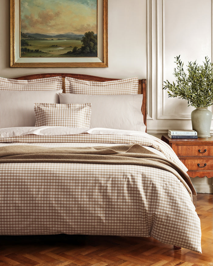 The Luxe Premium Percale Duvet Set in Camel Gingham features two pillows and a folded comforter with a beige and white gingham check pattern, neatly stacked on a white background.