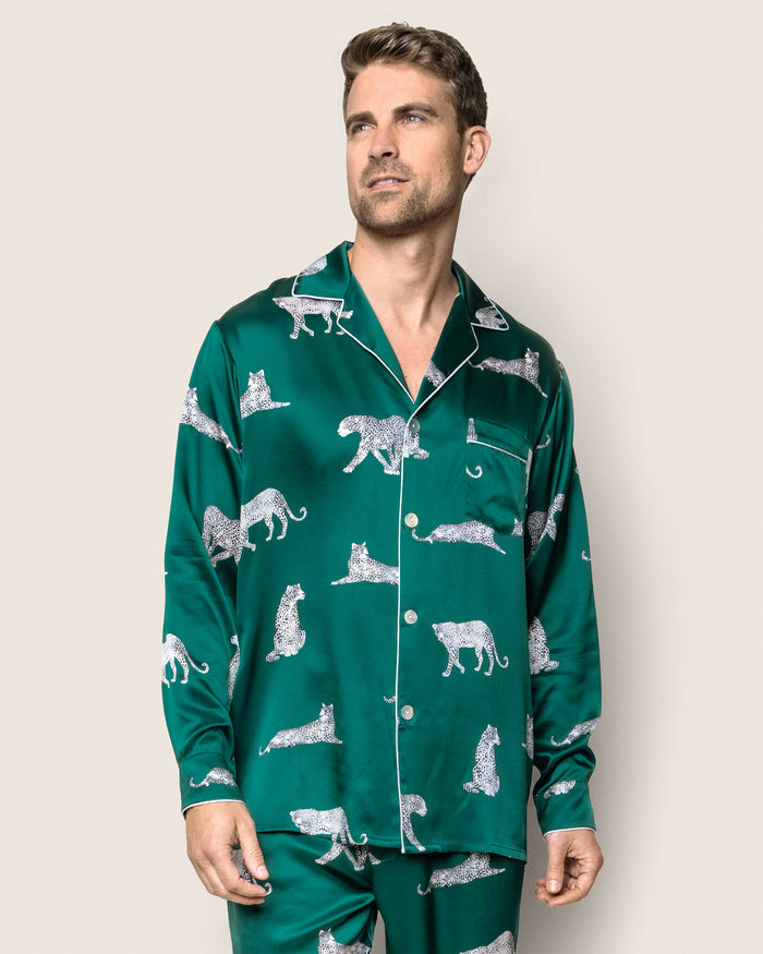 A person wearing Petite Plumes Mens Silk Pajama Set in Panthère de Luxe with a leopard print and white buttons. They have short hair, are looking upwards to the side, against a plain background.