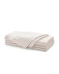 A neatly folded stack of Signature Twill Napkins in Camel Ticking, featuring thin beige and white stripes, displayed against a white background.