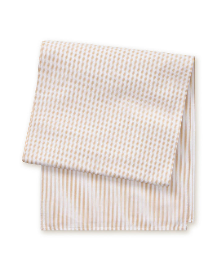 The Signature Twill Table Runner in Camel Ticking features thin, vertical tan and white stripes and is shown folded on a white background.