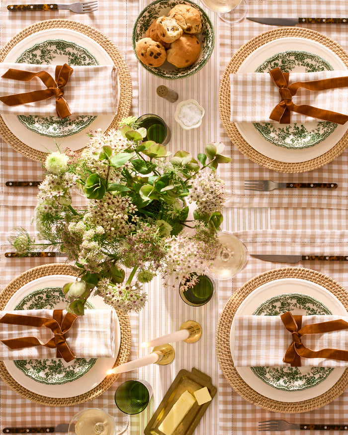 The Signature Twill Table Runner in Camel Ticking features thin, vertical tan and white stripes and is shown folded on a white background.
