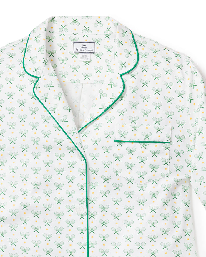 The Womens Twill Pajama Set in Match Point by Petite Plume includes a white top made from premium cotton, showcasing green piping, a playful pattern of green tennis rackets and yellow balls, and a chest pocket with green trim.