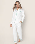 A person with long hair is wearing the Womens White Twill Pajama Set with Green Piping by Petite Plume. They are barefoot against a light background, smiling slightly and looking at the camera.